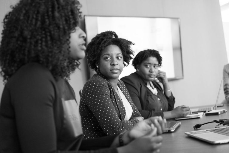 Black professional women discussing work in an office meeting